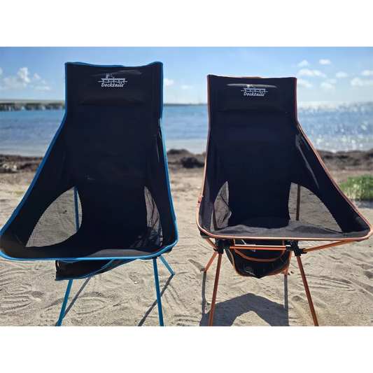 Two portable chairs on a sandy beach with water and sky in the background