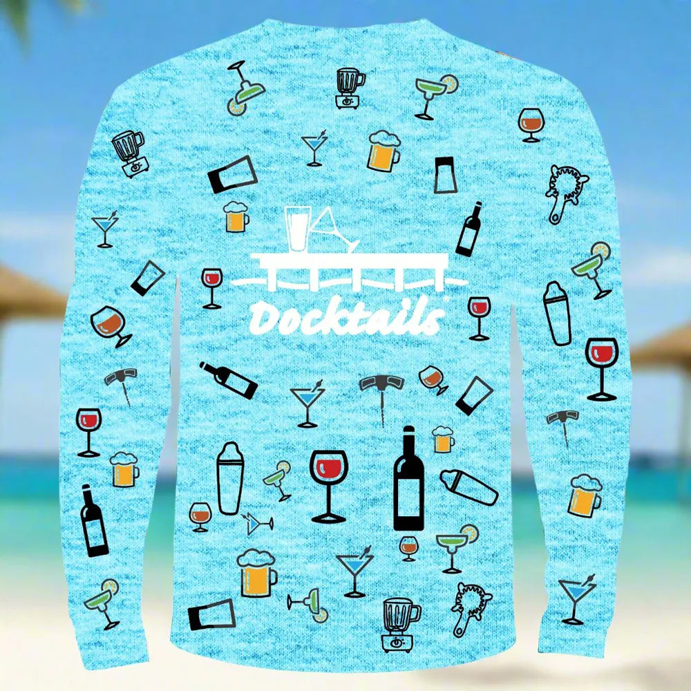 A light blue heather long-sleeve shirt with a 'Docktails' graphic and cocktail-themed illustrations, shown against a blurred beach background.