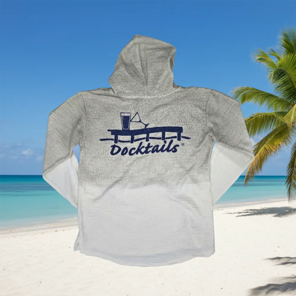 A heather beige hooded long-sleeve shirt with a white gradient hem and a navy blue 'Docktails' graphic on the back, shown against a tropical beach background with blue sky, ocean, and palm tree.
