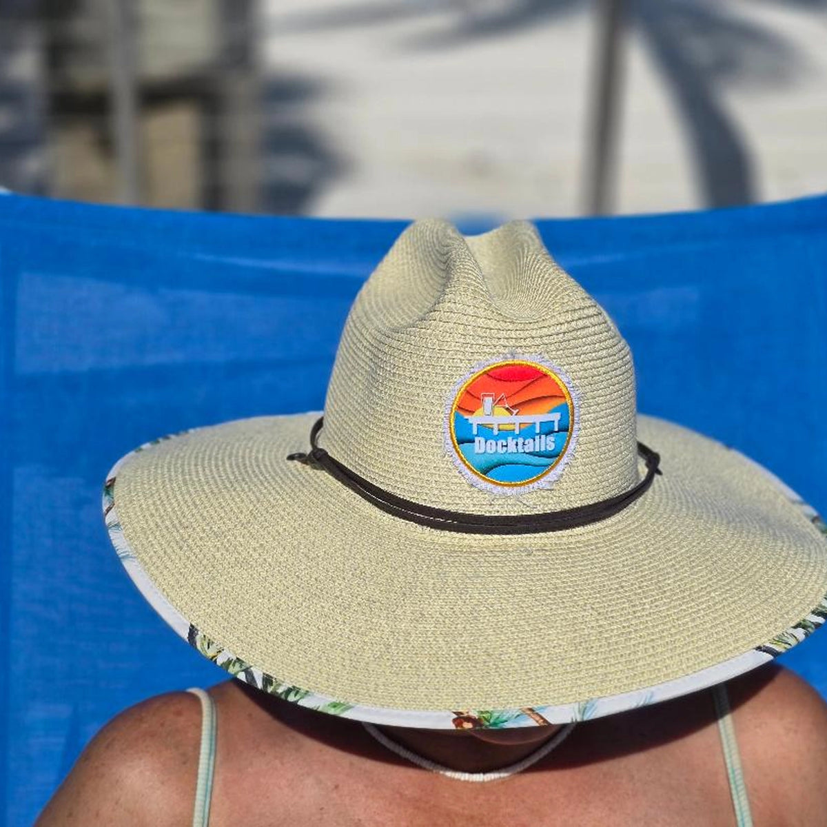 Woman wearing beige straw hat with a brightly colored Docktails logo patch