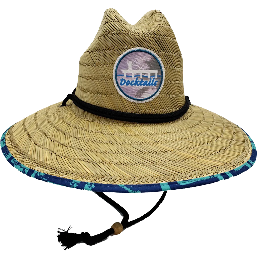 Wide brim lifeguard hat with thin brown fabric band and chin strap with a wooden bead. Edge of brim has turquoise and navy fabric. Crown has a Docktails logo patch.