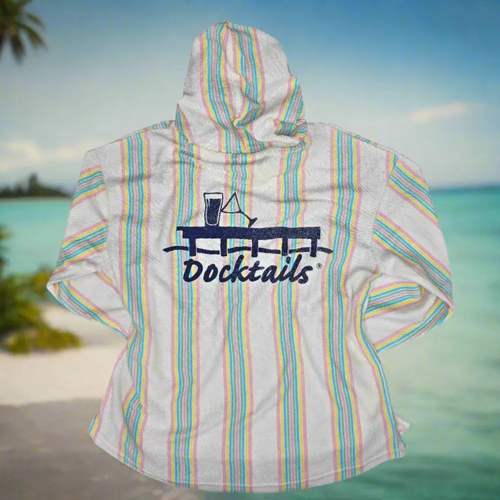 A long-sleeve hoodie with vertical pastel stripes in pink, blue, and yellow on an off- white base, featuring a dark navy graphic of a cocktail and the word 'Docktails' on the back, shown against a tropical beach background.